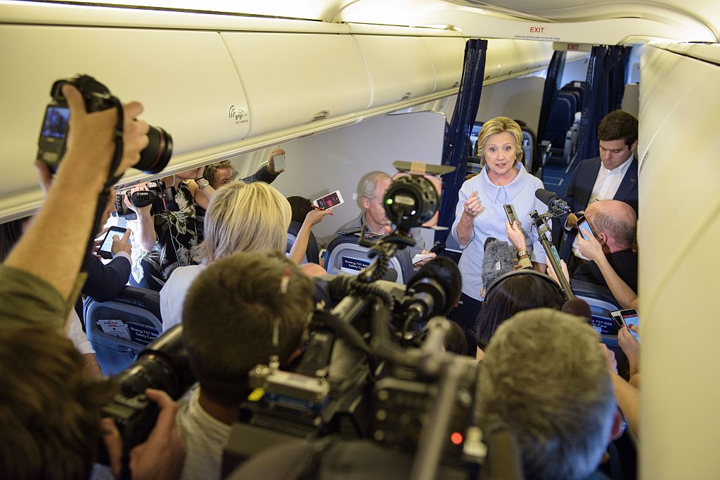 Hillary Clinton talks to the press on her campaign plane