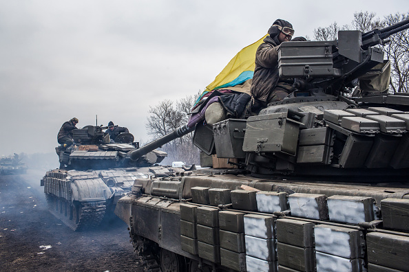 A Ukrainian serviceman walks past reconditioned armoured personnel carriers.