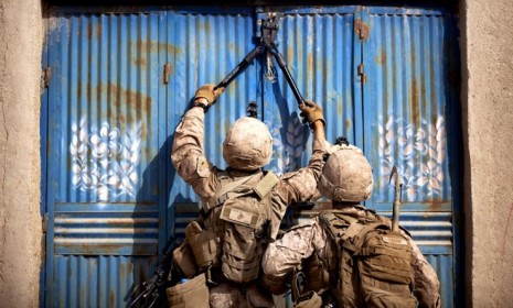 U.S. Marines work to open a door while searching for explosives