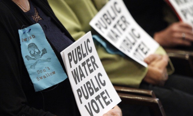 Protestors hold signs in Portland&#039;s City Hall during a 2012 vote to add fluoride to the city water.
