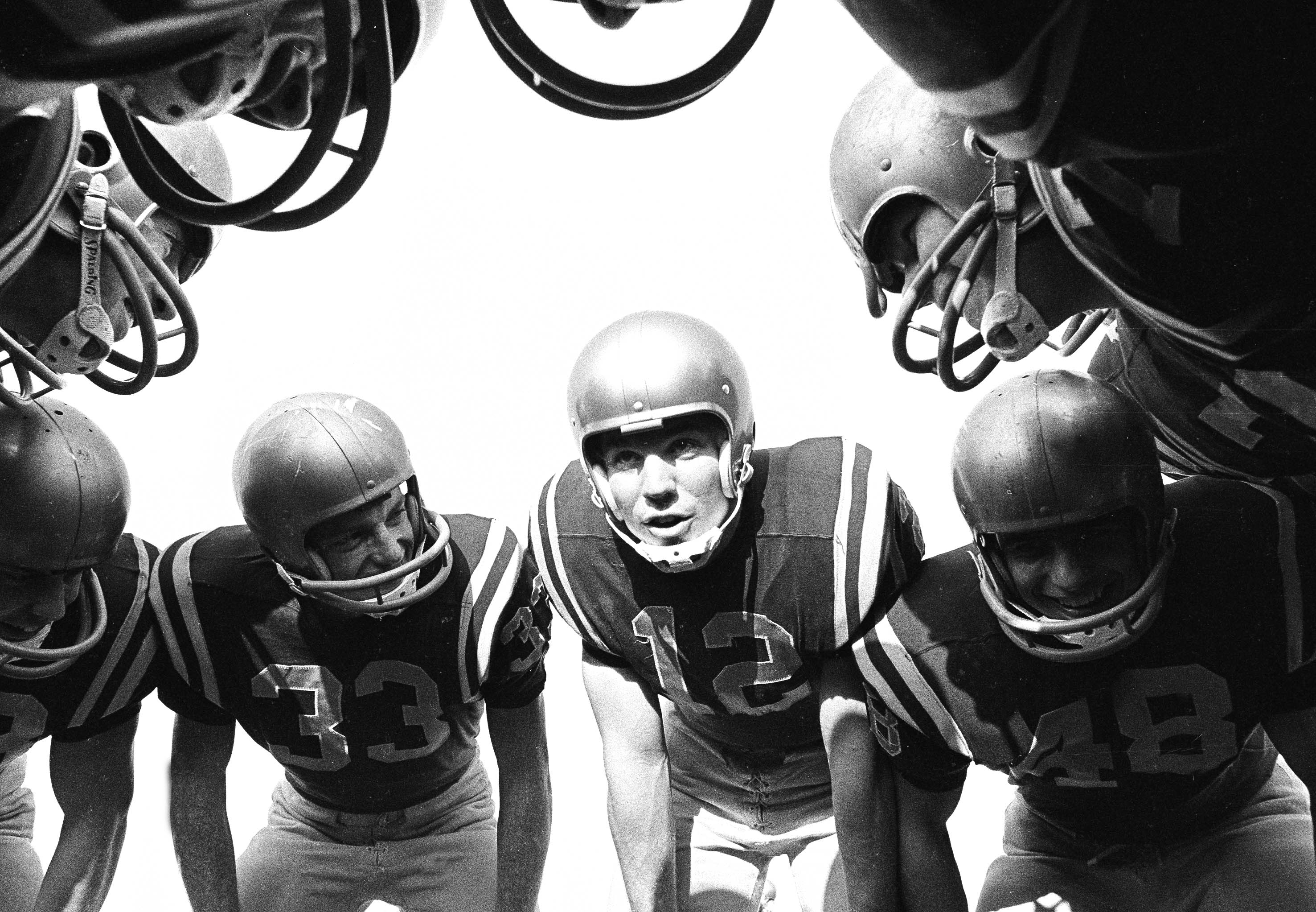 Football players huddle, 1963.