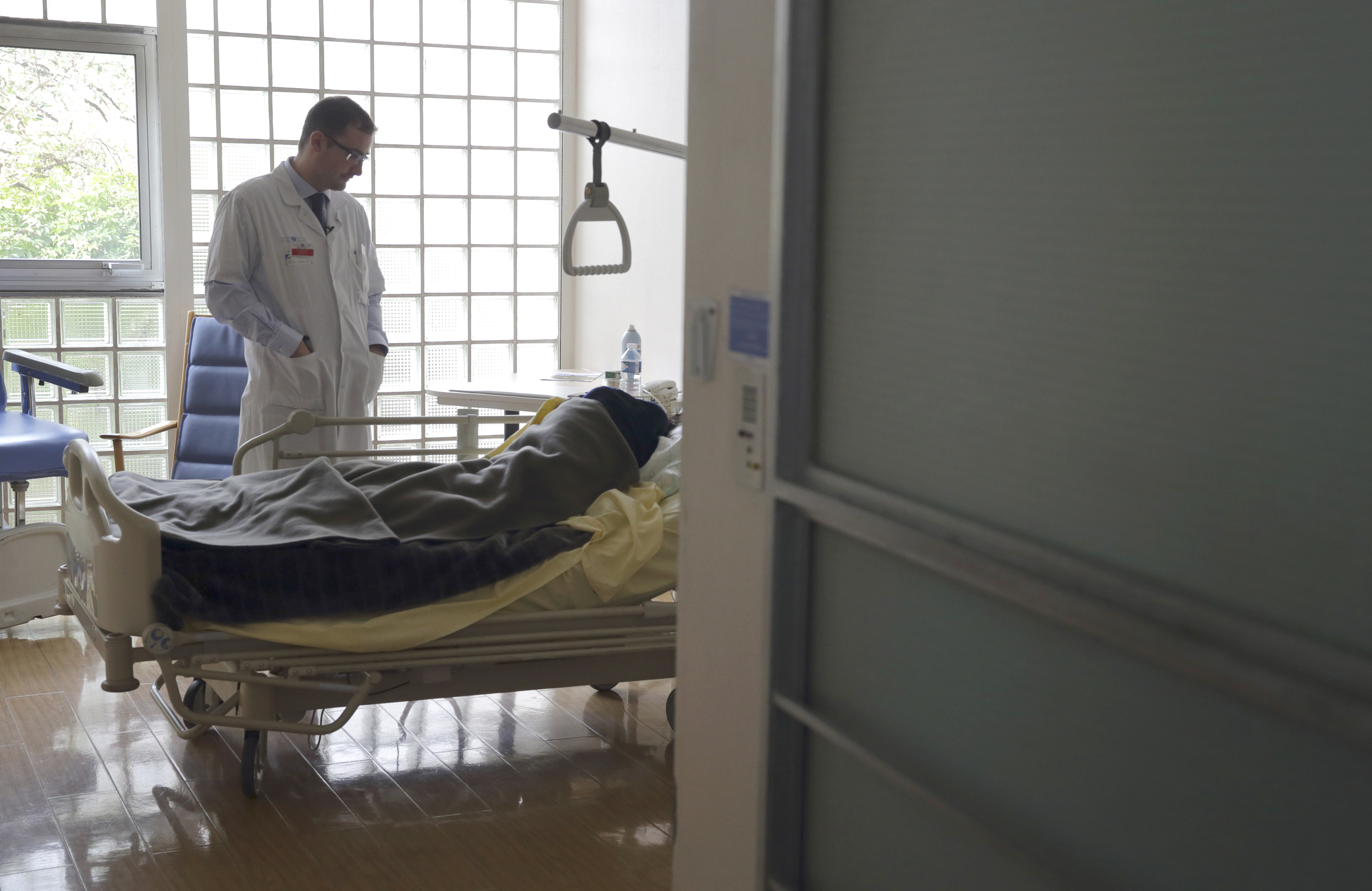 Dr. Stephane Mercier, Head of the palliative care unit, visits a patient in a hospital near Paris.