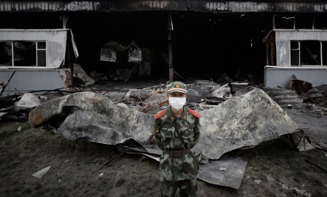 A policeman stands guard outside the burned out poultry slaughterhouse 