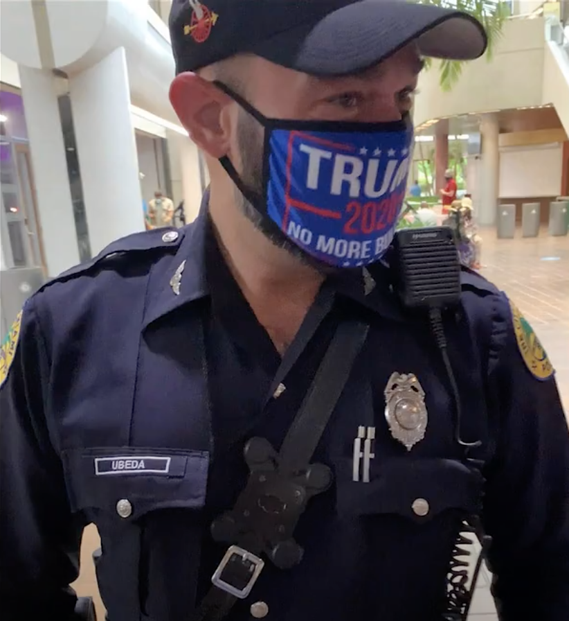 A Miami police officer in a pro-Trump mask at a voting site.