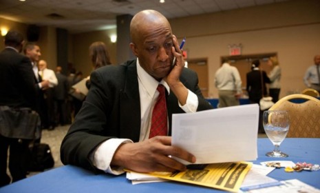 A man peruses paperwork at a New York City job fair in April