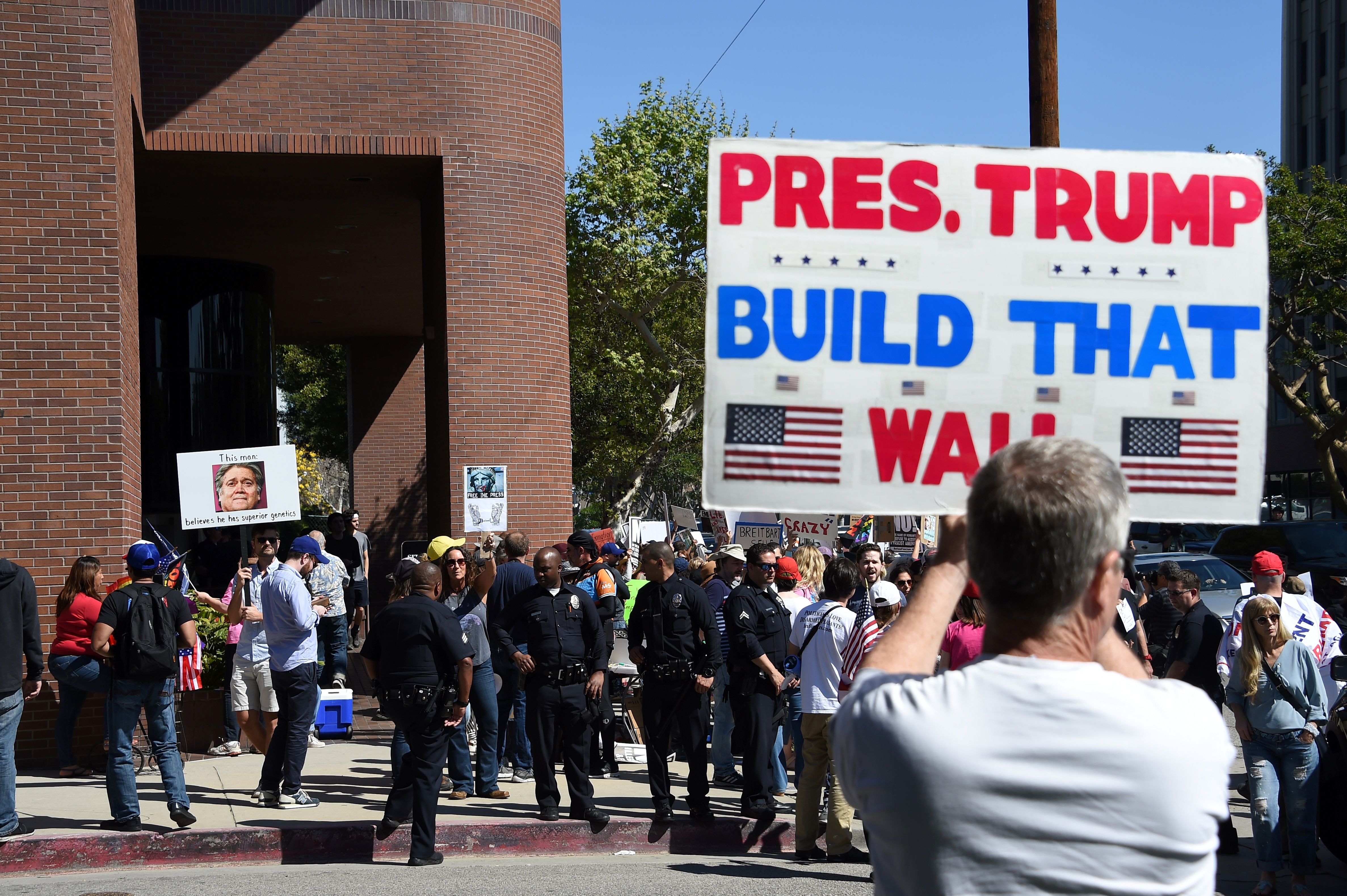 A demonstrator holds a sign supporting a border wall. 