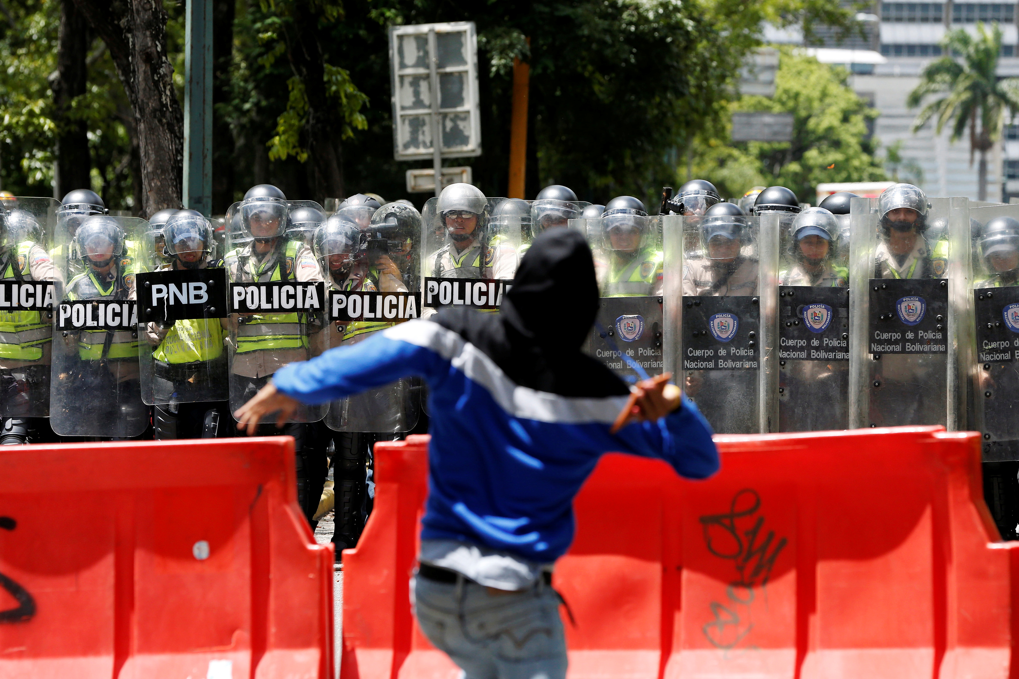 A demonstrator throws a stone at riot police officers during a student protest in Caracas, Venezuela.