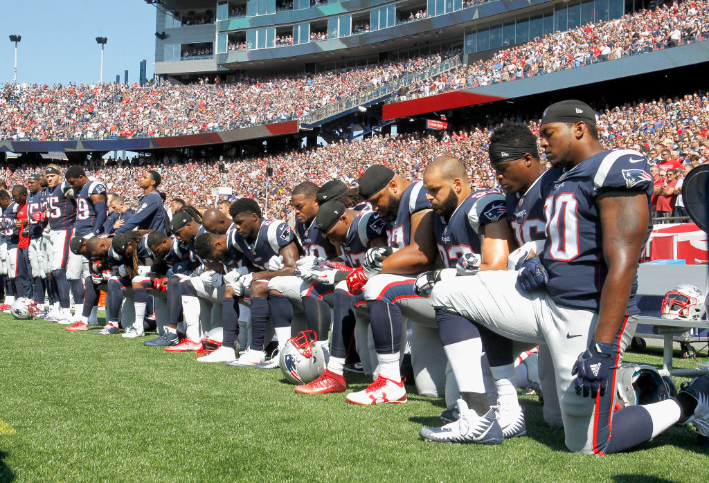 Members of the New England Patriots kneel during the National Anthem.