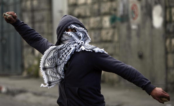 A young Palestinian man prepares to throw a stone.