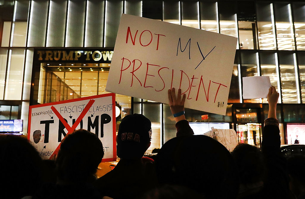 Trump protestors hold sign.