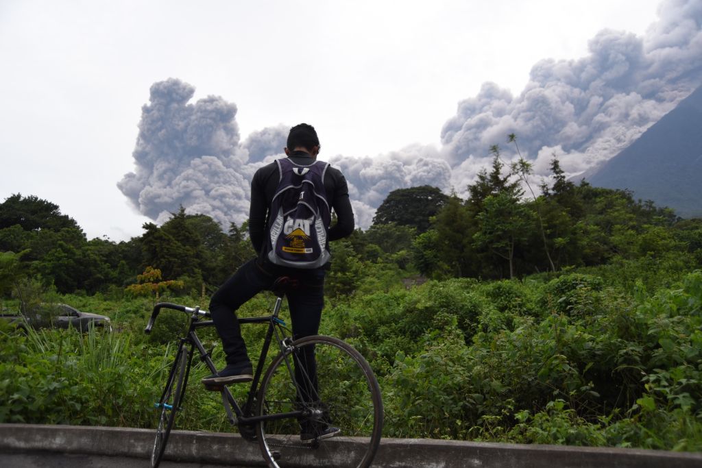 A man looks out on the erupting Volcán de Fuego.