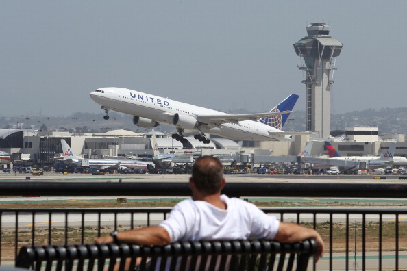 A man watches a United Airlines jet take off from LAX.