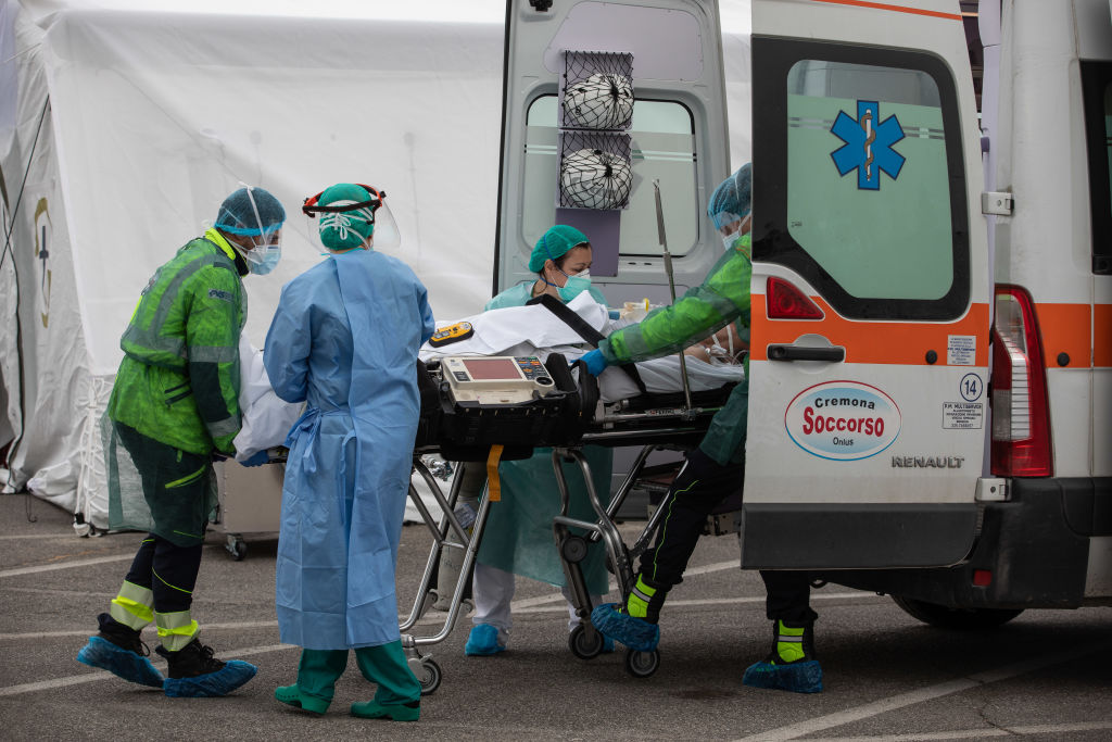 Italian health care workers load a patient in an ambulance.