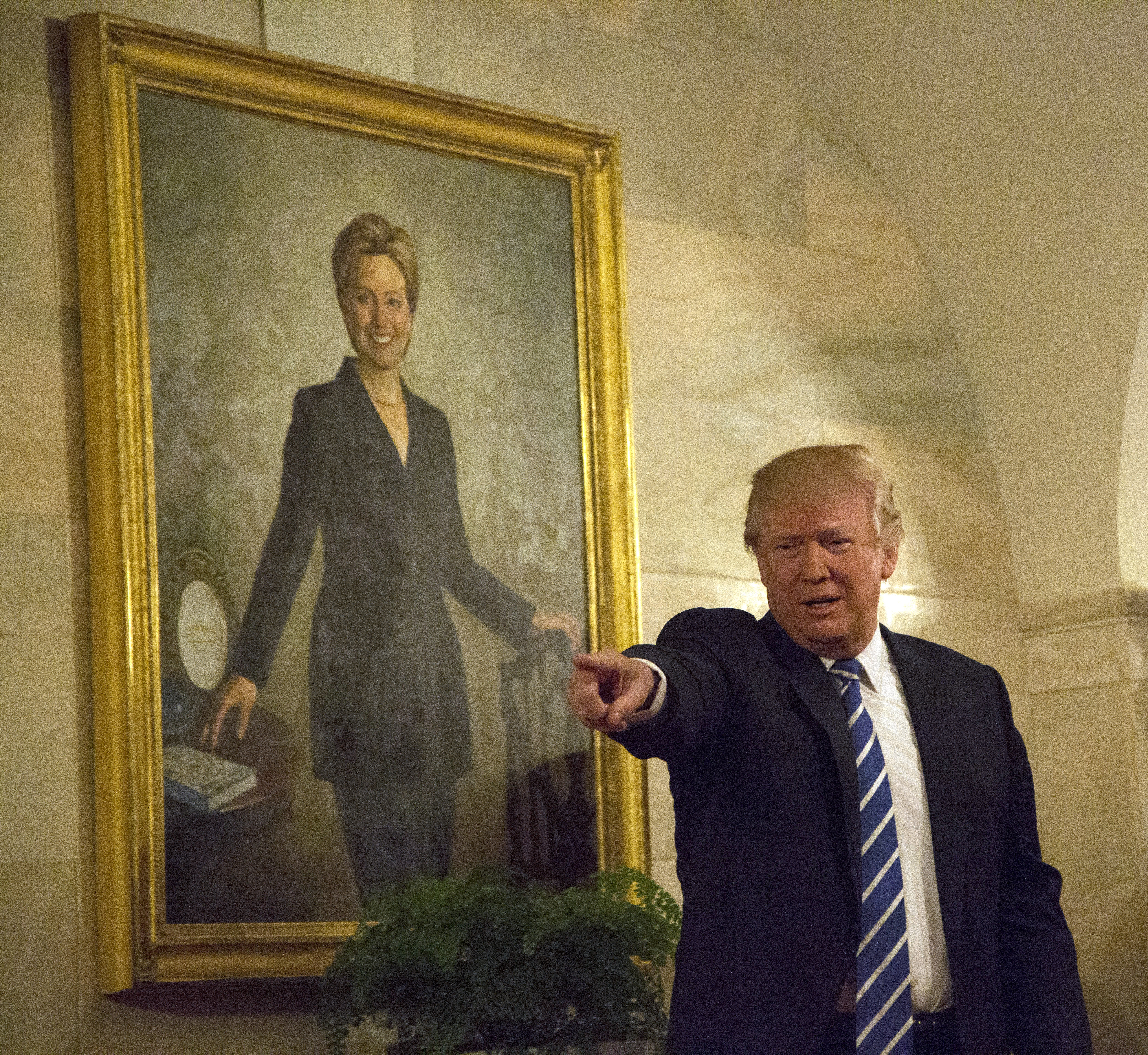 Trump stands in front of a painting of Hillary Clinton
