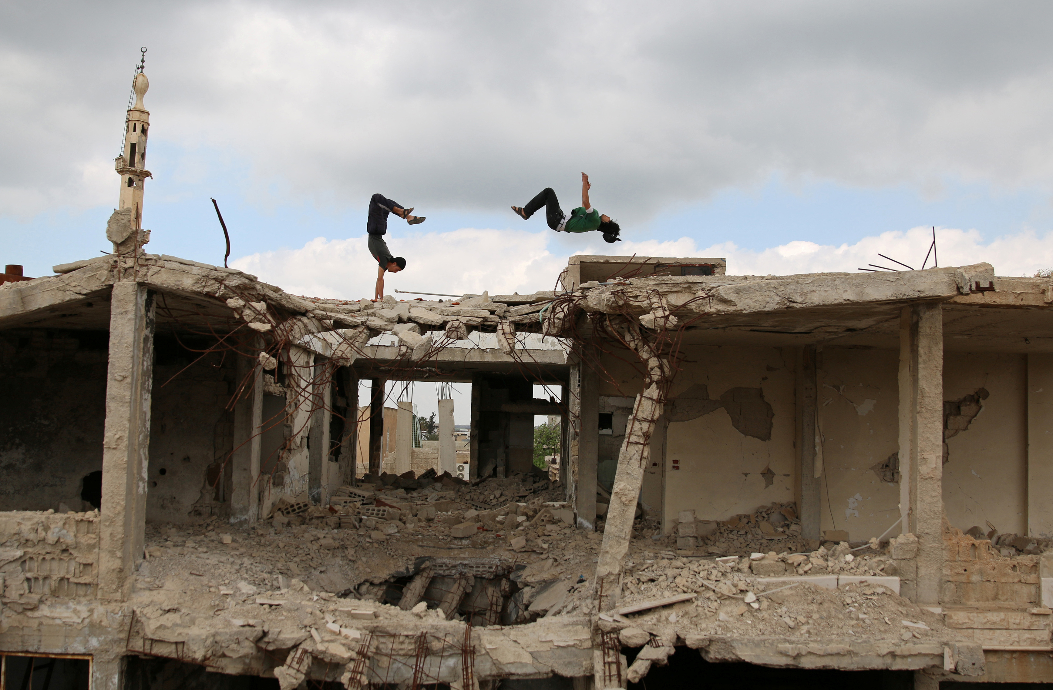 Syrian teenagers perform Parkour moves atop city ruins.