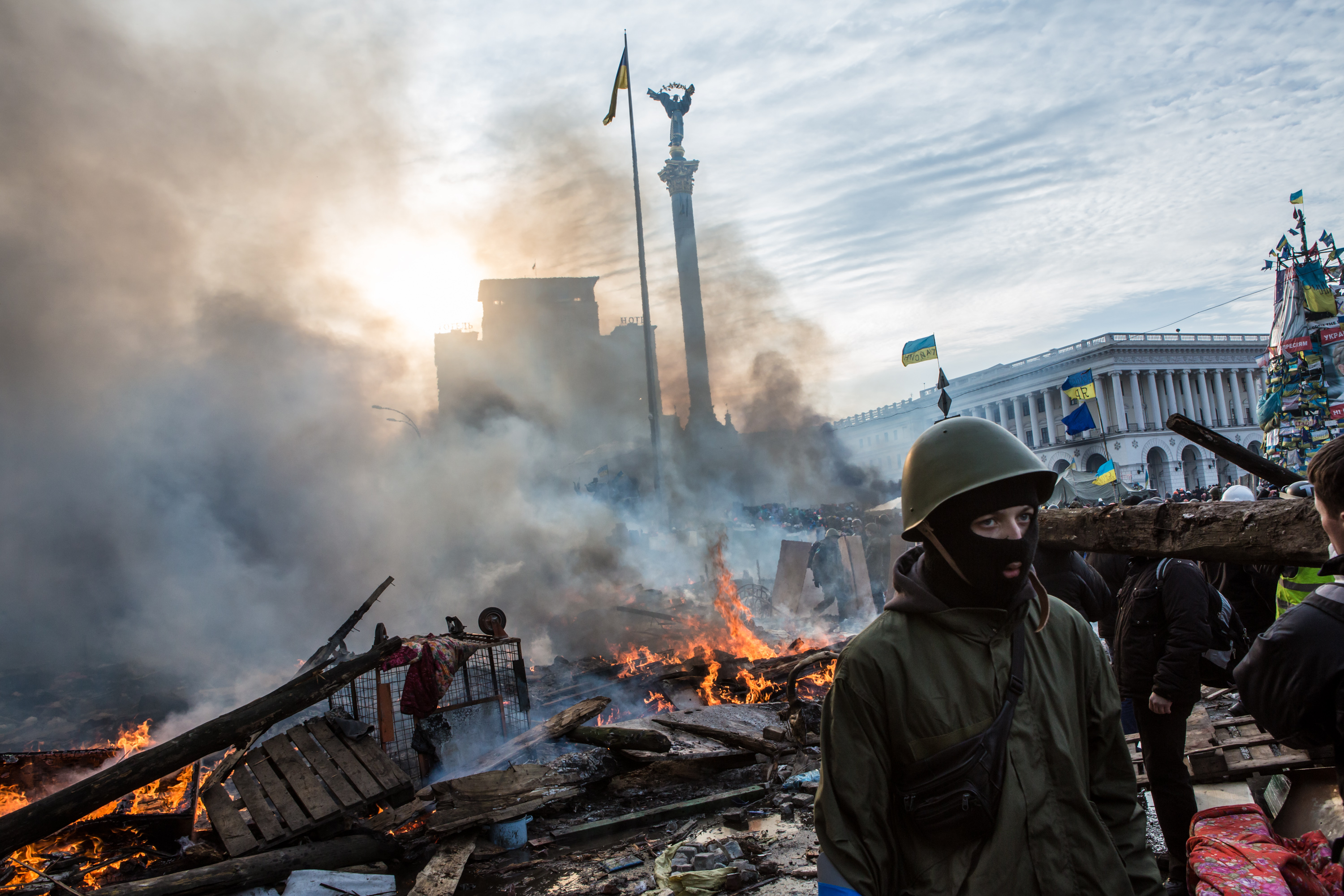 Anti-government protesters walk amid debris and flames near the perimeter of Independence Square, known as Maidan, on February 19, 2014 in Kiev, Ukraine.