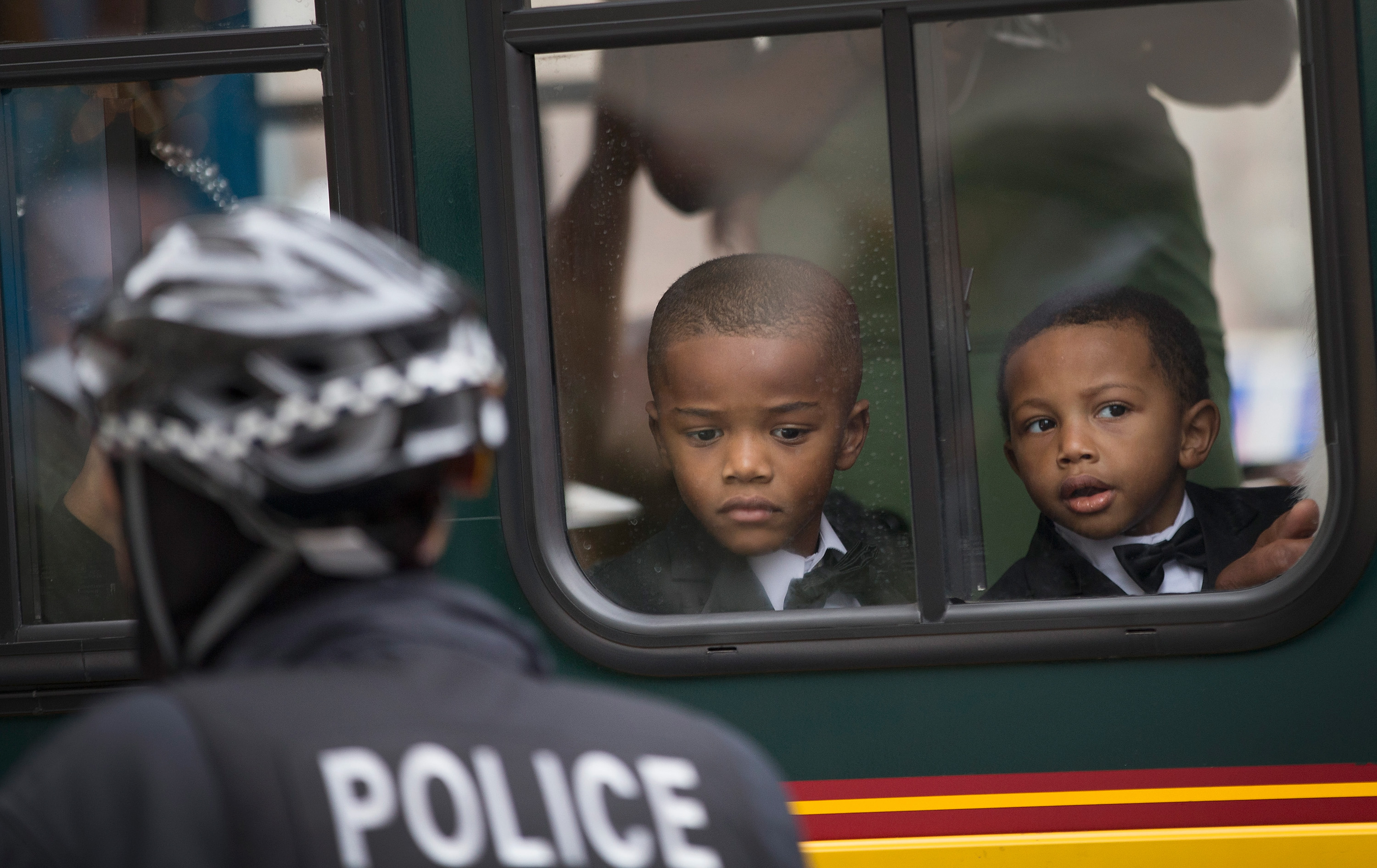 Boys watch from a seat in a charter bus as demonstrators march in protest of police abuse in Chicago.