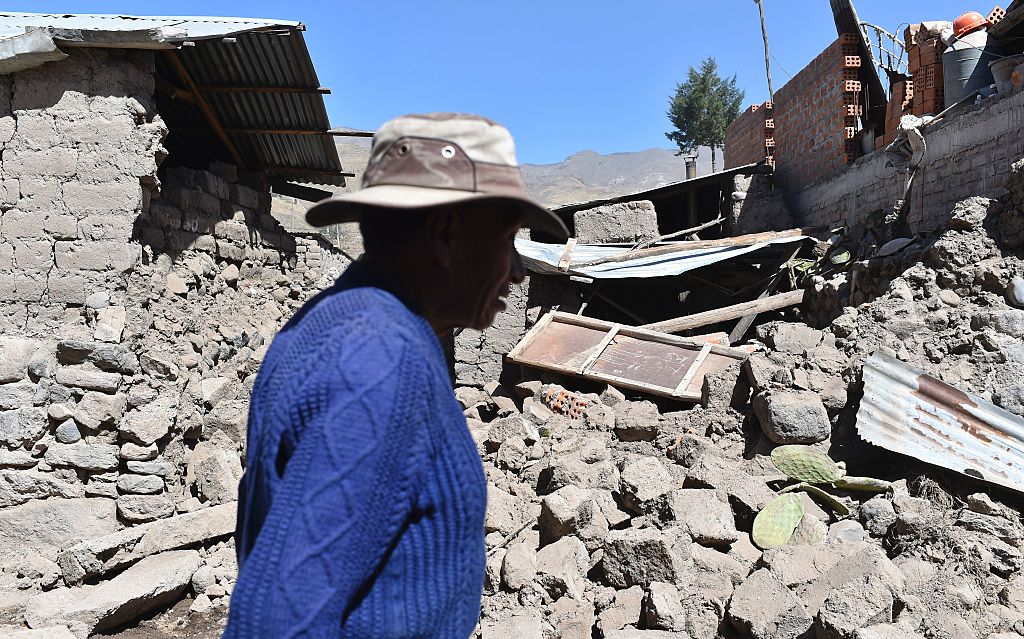 A man walks by toppled houses on August 15, 2016 in the Andean town of Yanque in southern Peru, after a 5.3 magnitude earthquake struck this remote picturesque region in the state of Arequipa