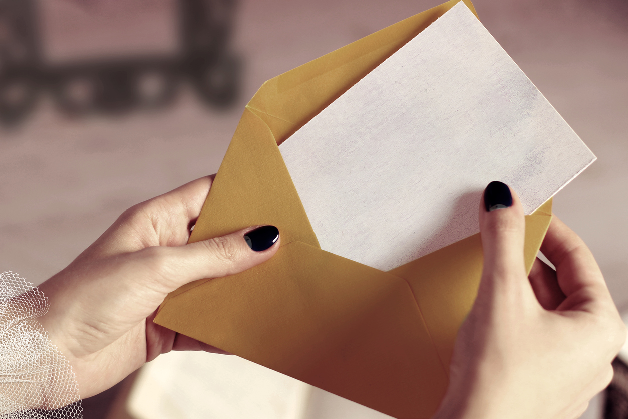 A woman opens an envelope.