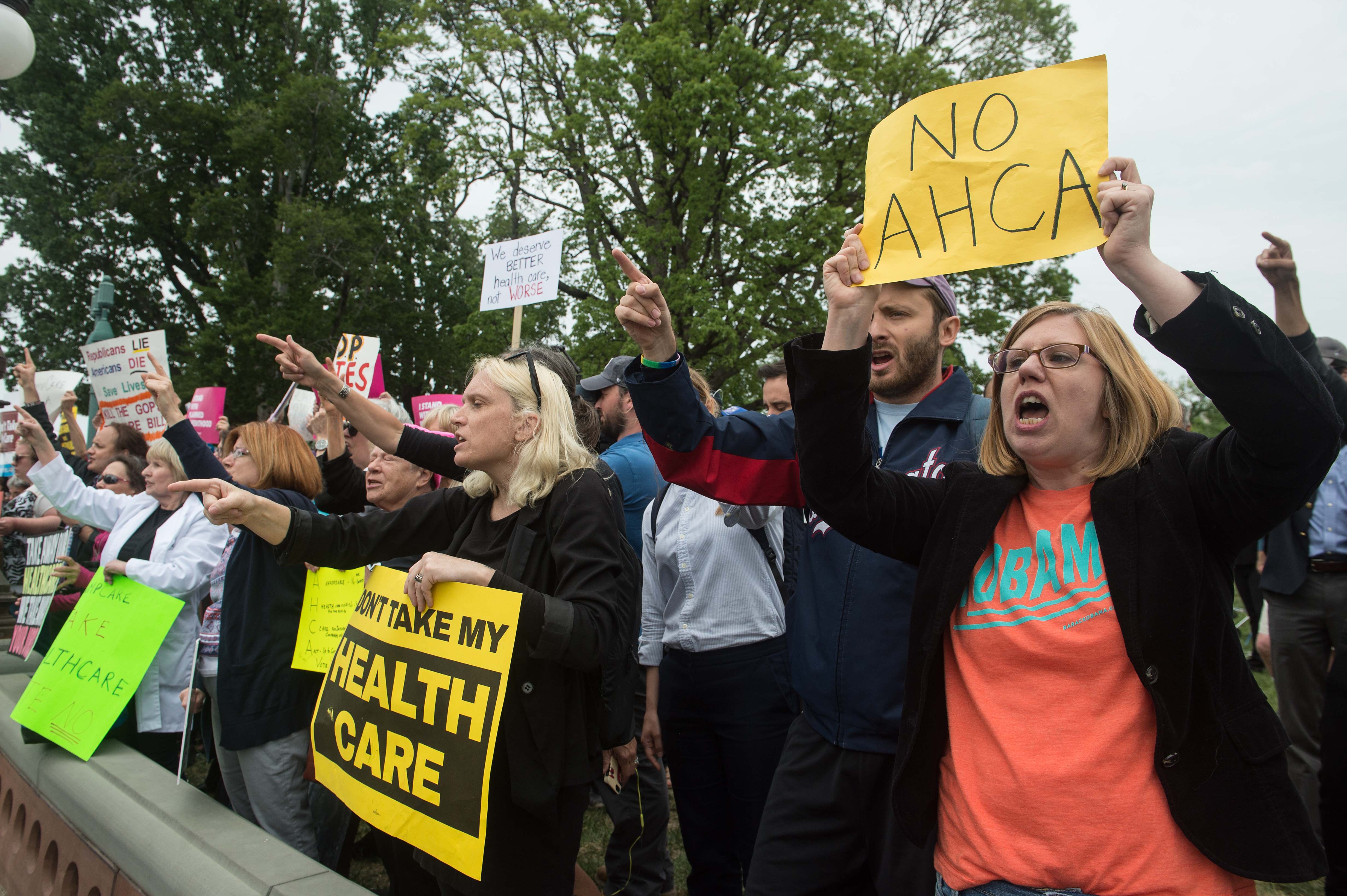 Protesters holding signs about the AHCA