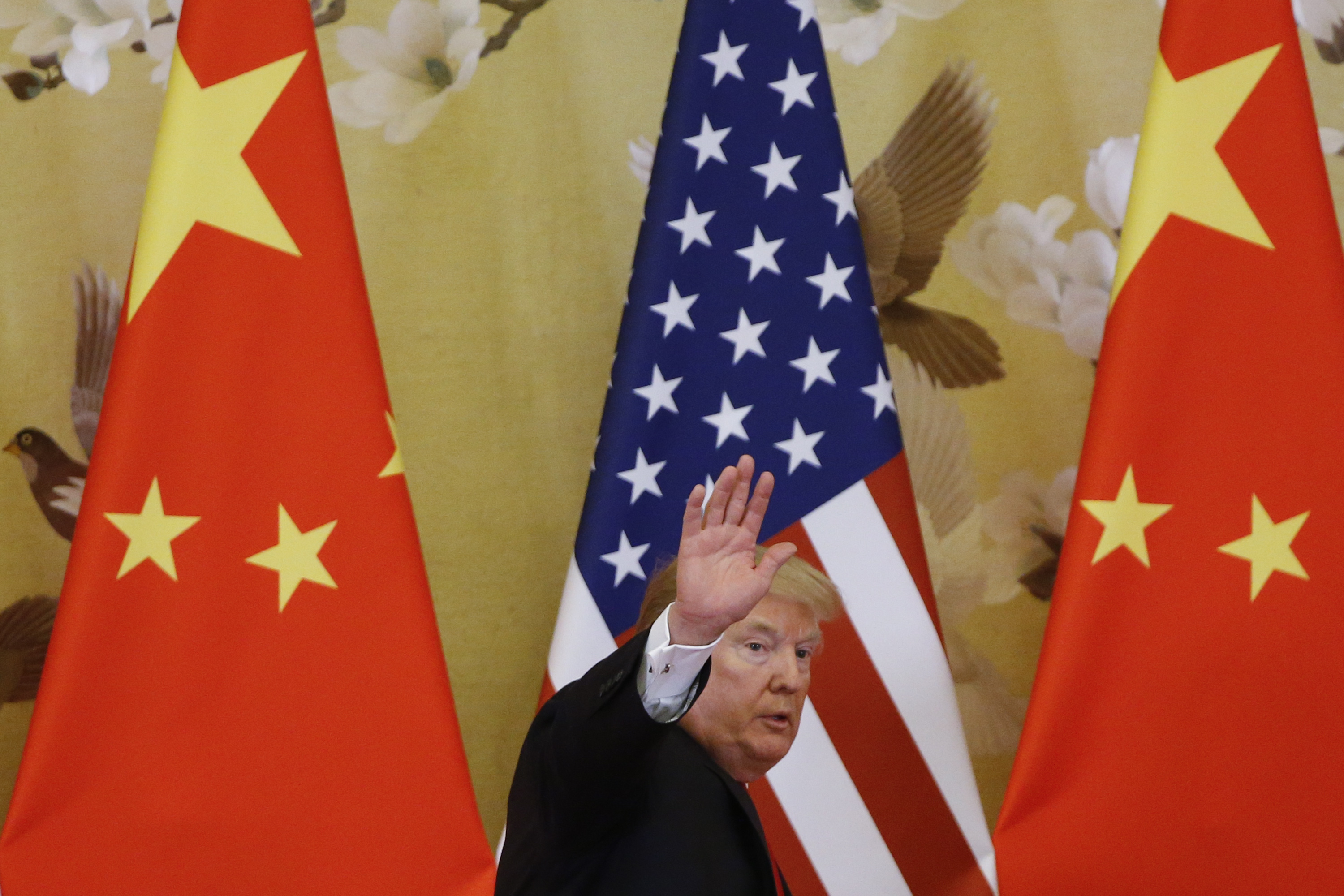 President Trump walks away from a red Chinese flag and toward an American flag while waving goodbye