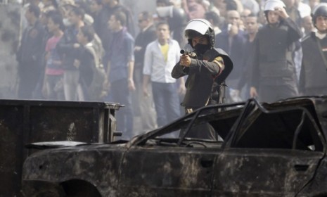 A policeman fires a shotgun with rubber bullets at protesters during clashes in Tahrir Square: Egyptians continue to demand that the country&#039;s military leaders hand over power to civilians.