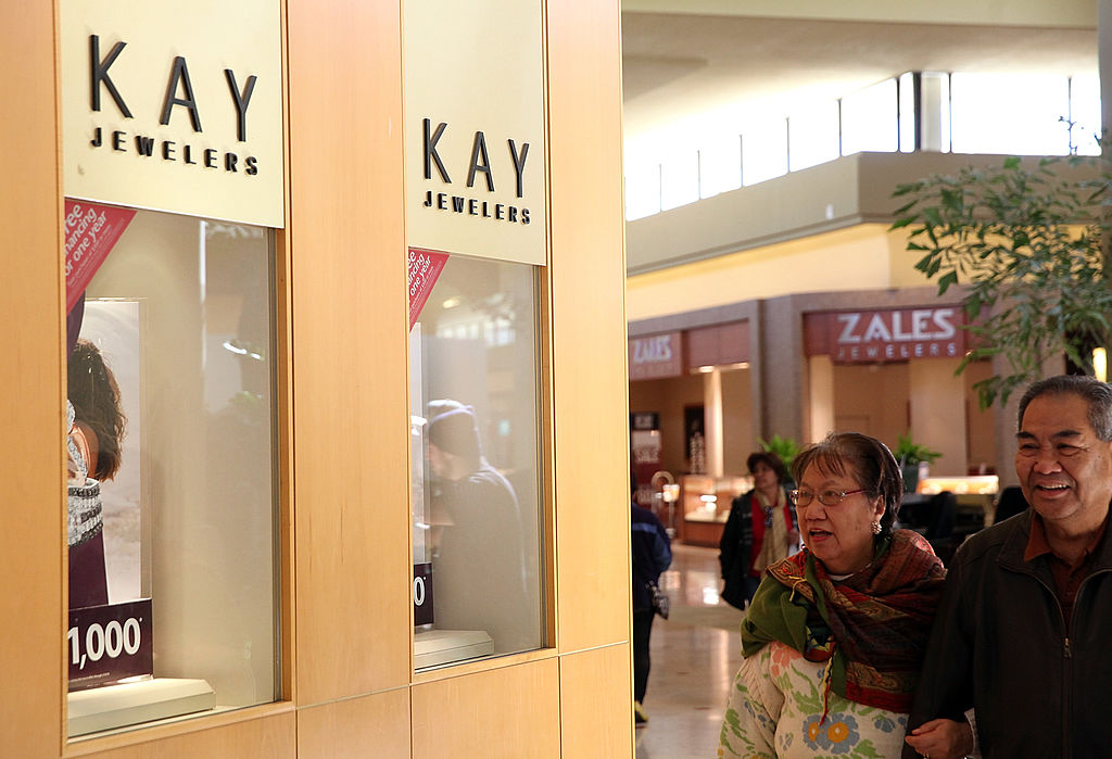 Shoppers walk by a Kay Jewelers and Zales.