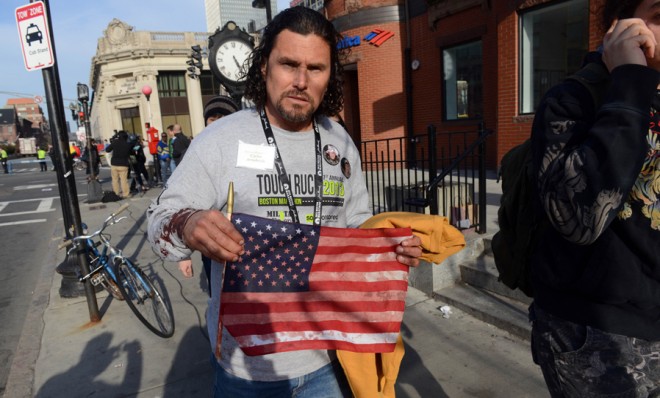 Carlos Arredondo, one of the civilian heroes who helped the wounded at the Boston Marathon, leaves the scene with a blood-soaked flag on April 15.