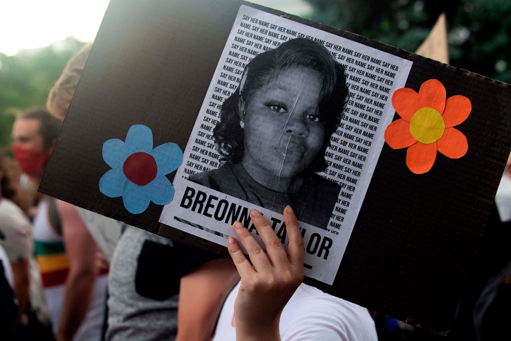 A protester holds a sign with Breonna Taylor&#039;s picture.