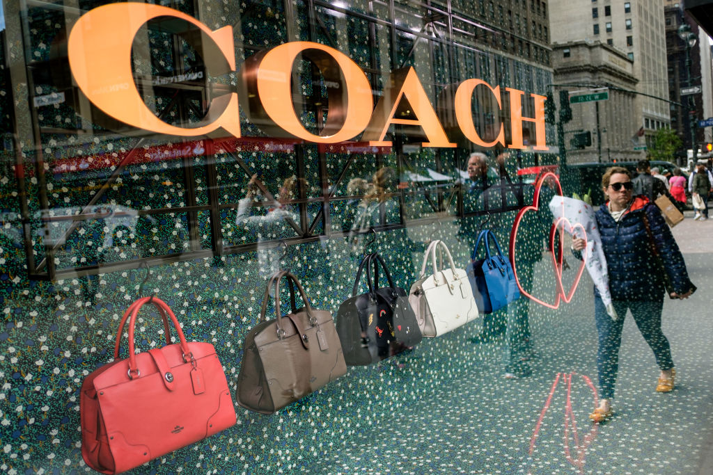 Woman passing a Coach luxury handbag store.