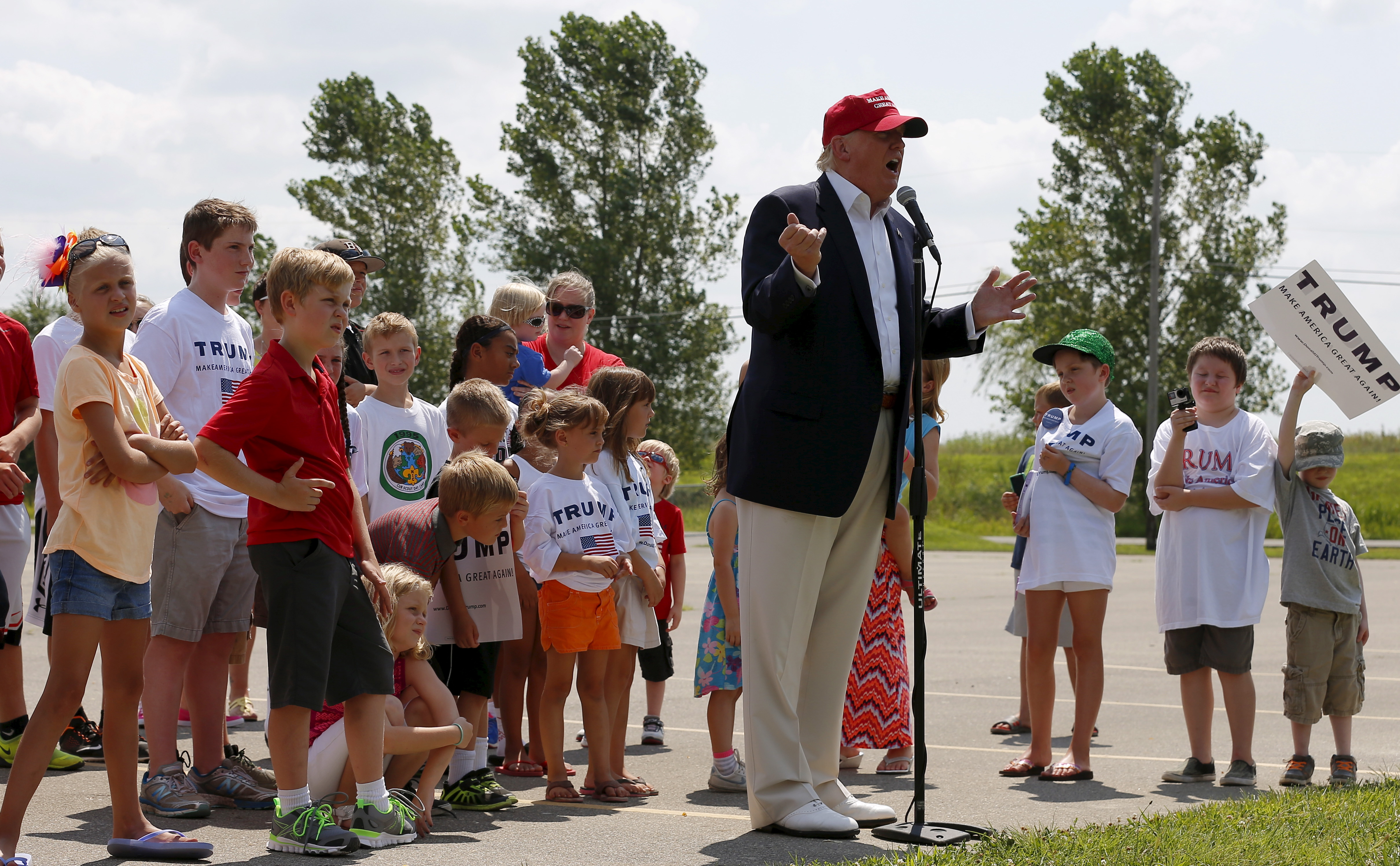 Donald Trump is surrounded by a group of kids.