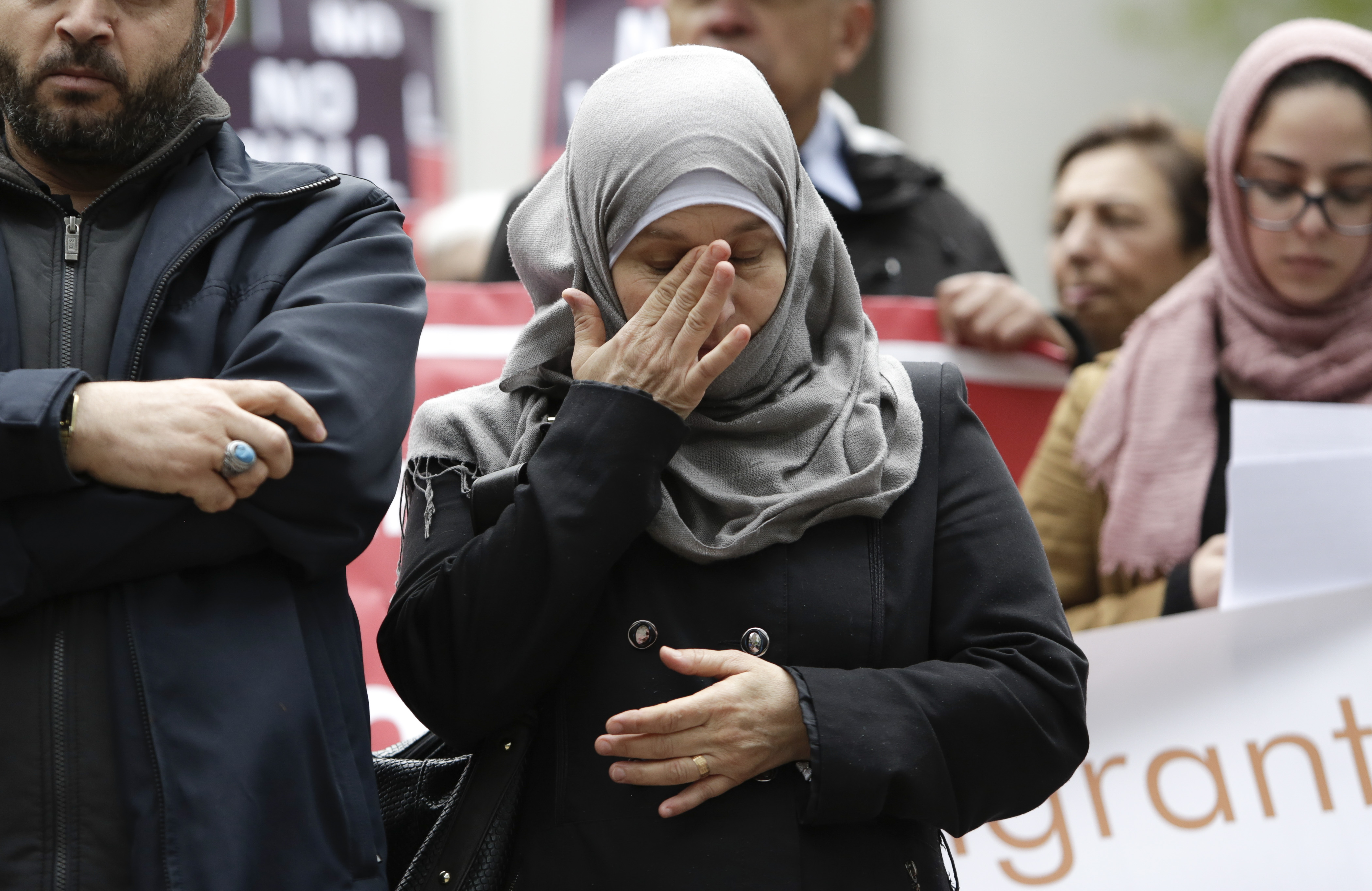 A Syrian refugee wipes her eyes at a rally protesting President Trump&#039;s travel ban.