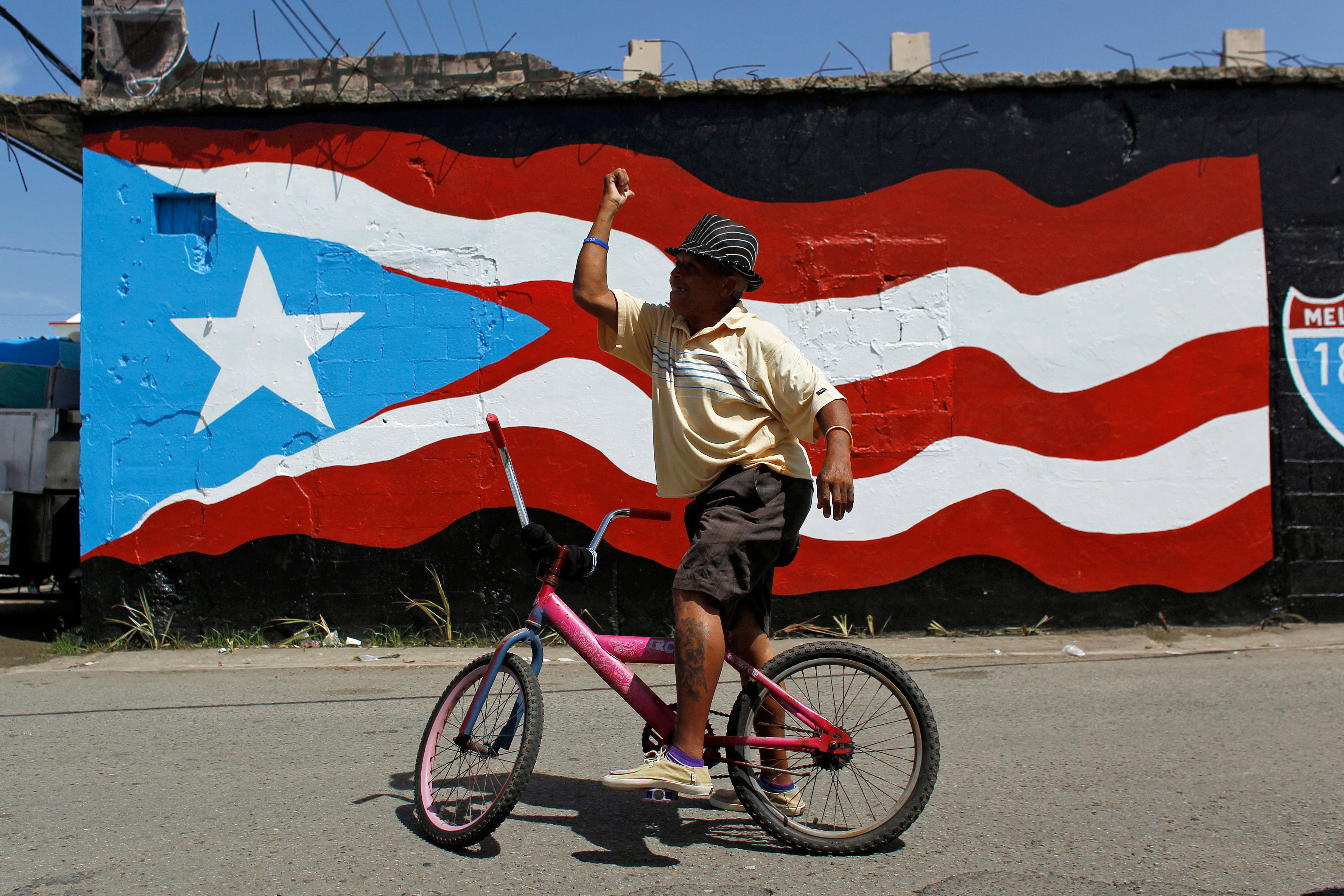 A man gestures on a bike in Puerto Rico.