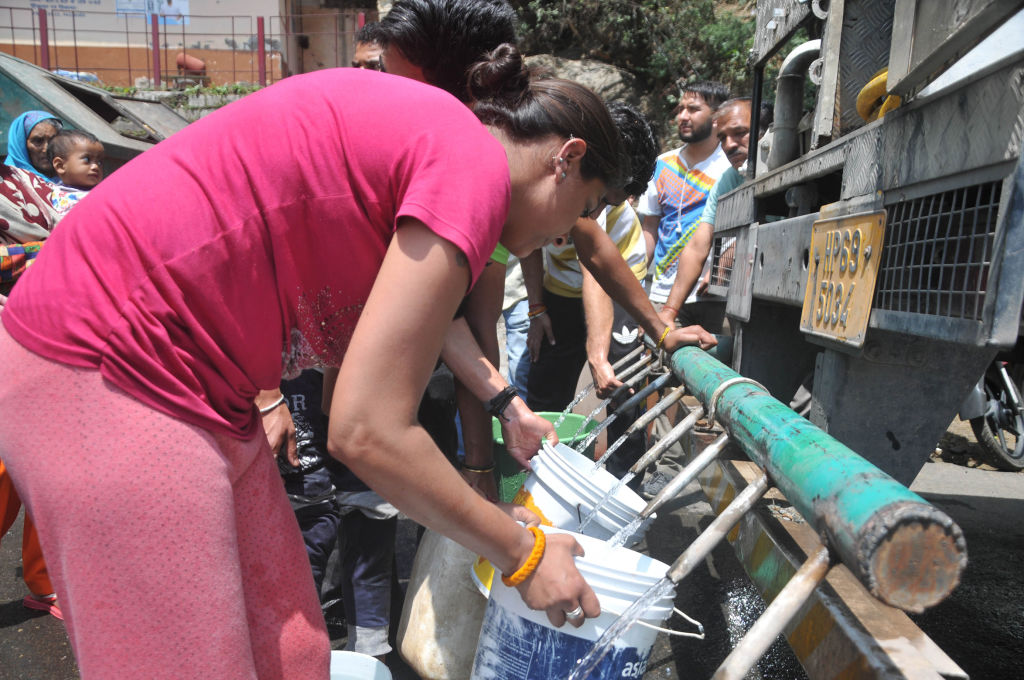 People fill up water jugs from a tanker in India.