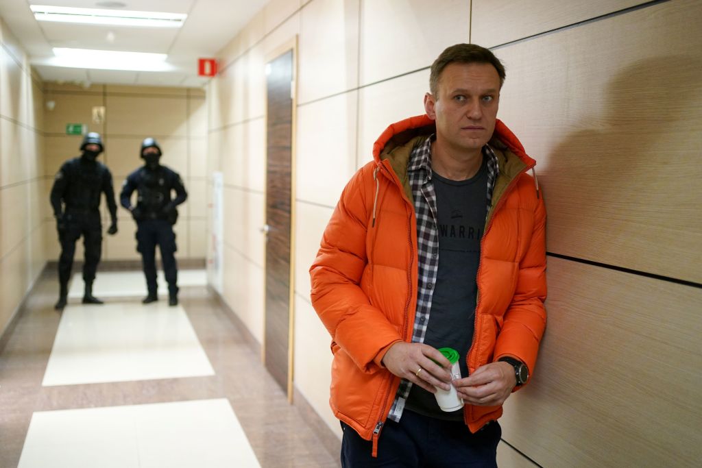Russian opposition leader Alexei Navalny stands near law enforcement agents in a hallway of a business centre, which houses the office of his Anti-Corruption Foundation (FBK), in Moscow on De