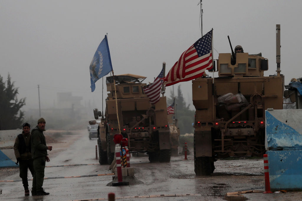 U.S. military vehicles drive through a checkpoint in Syria