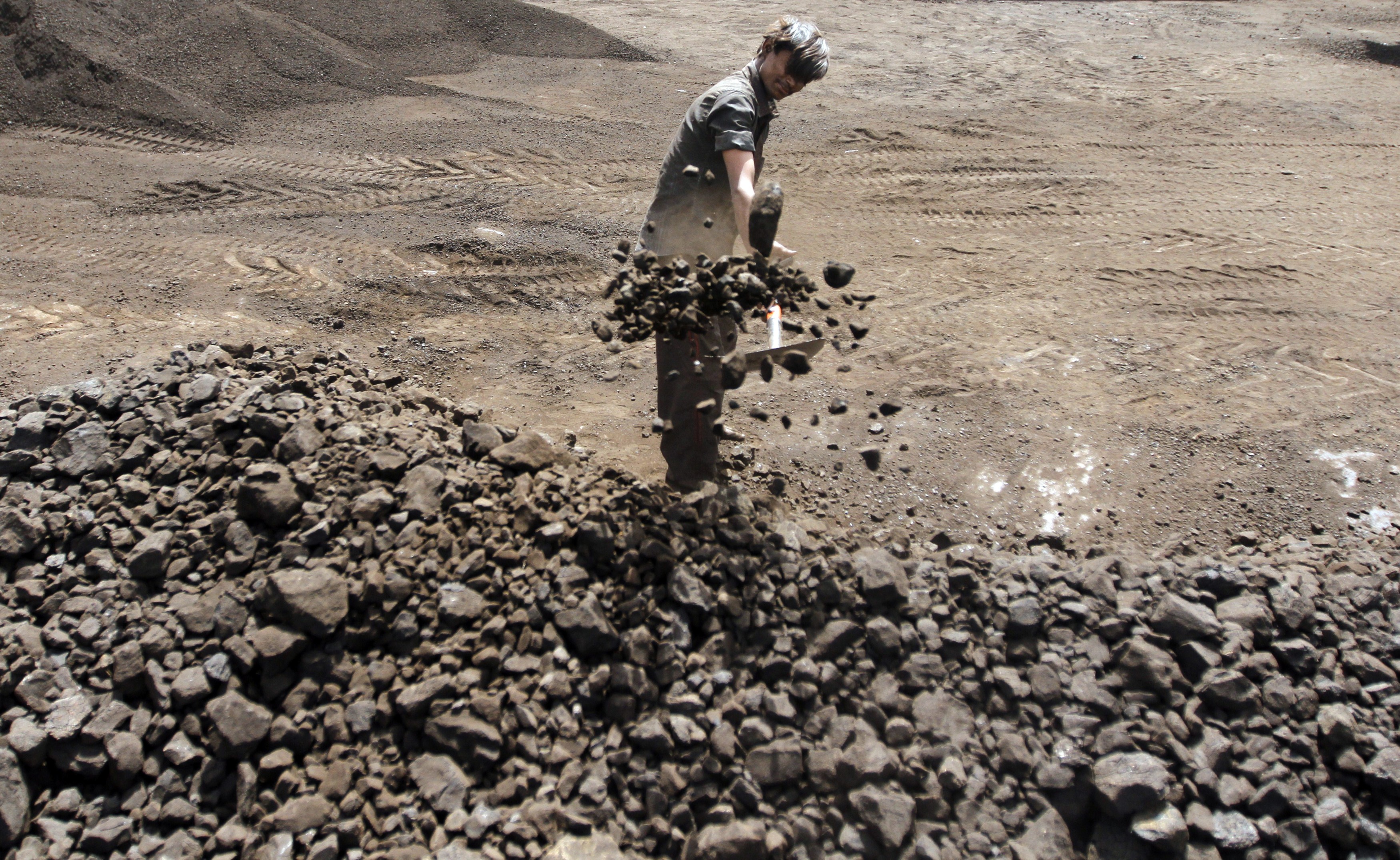 A worker shovels coal in a coal deposit yard.
