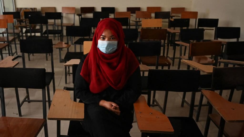 An Afghan girl sits in an empty classroom.