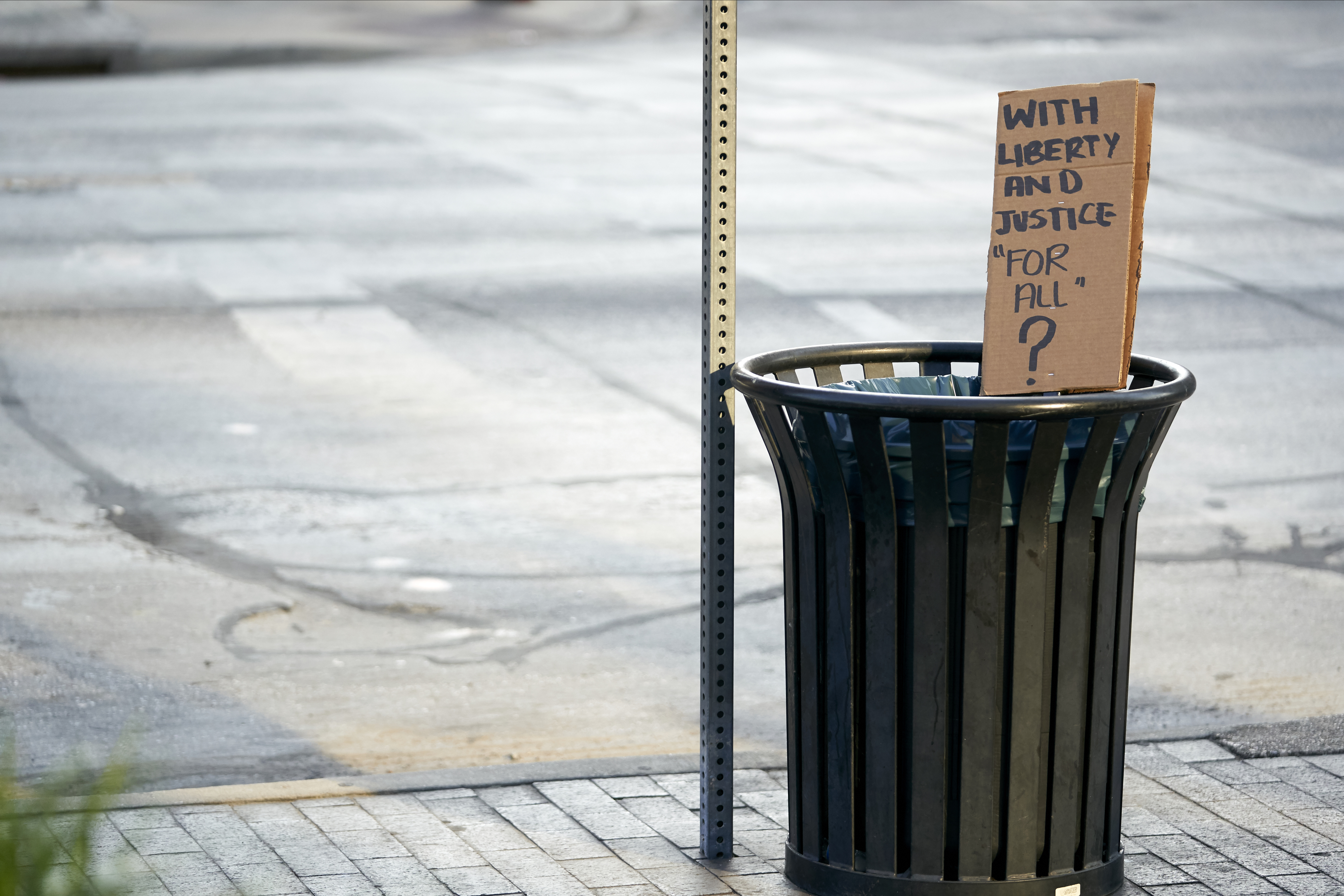 A sign protesting police brutality is seen in a Dallas trash can
