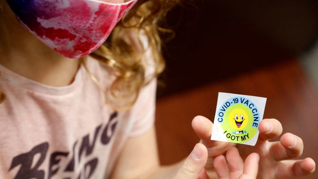 A child holds a sticker after being vaccinated.