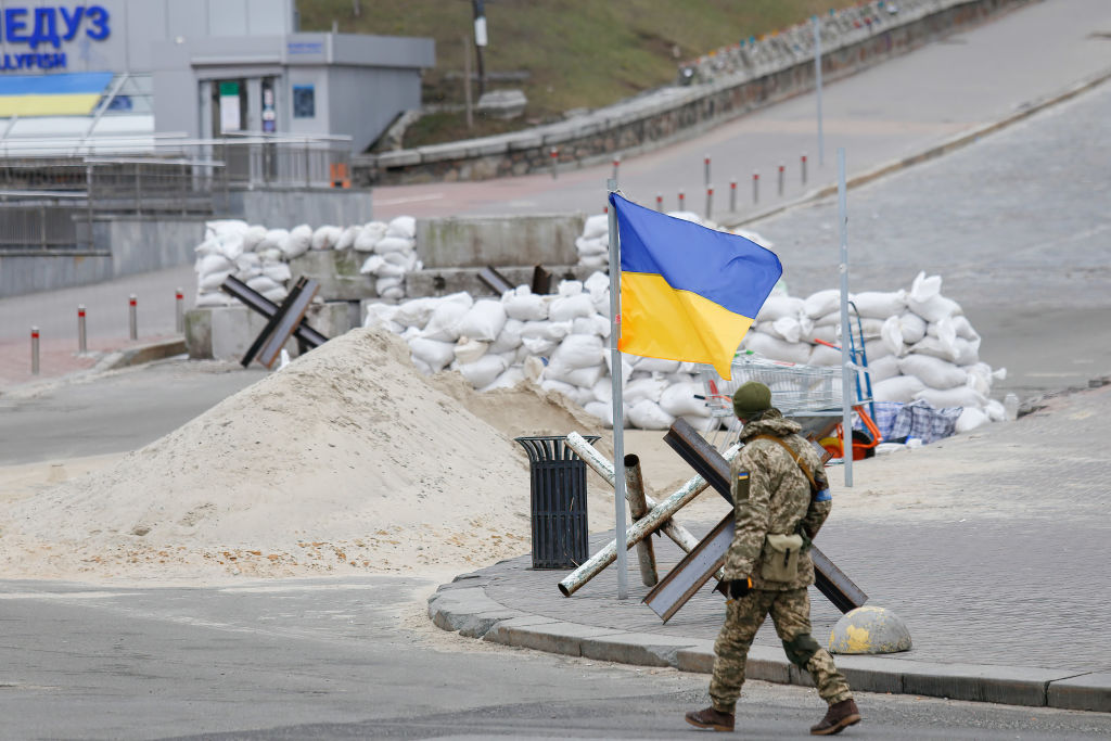 Ukrainian soldier walking near Ukrainian flag