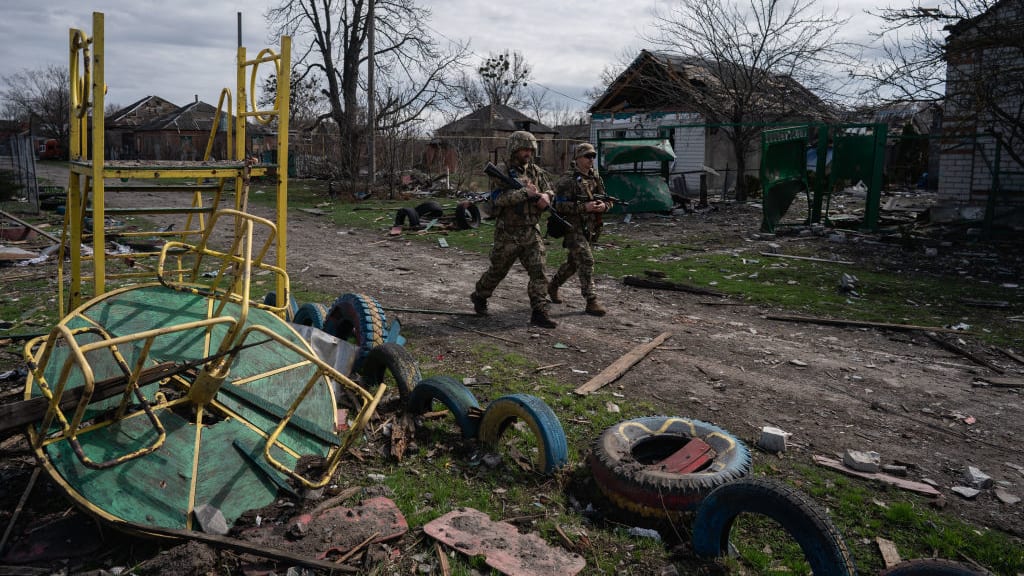 Ukrainian soldiers walk down a street damaged by Russian shelling in Kharkiv Oblast.