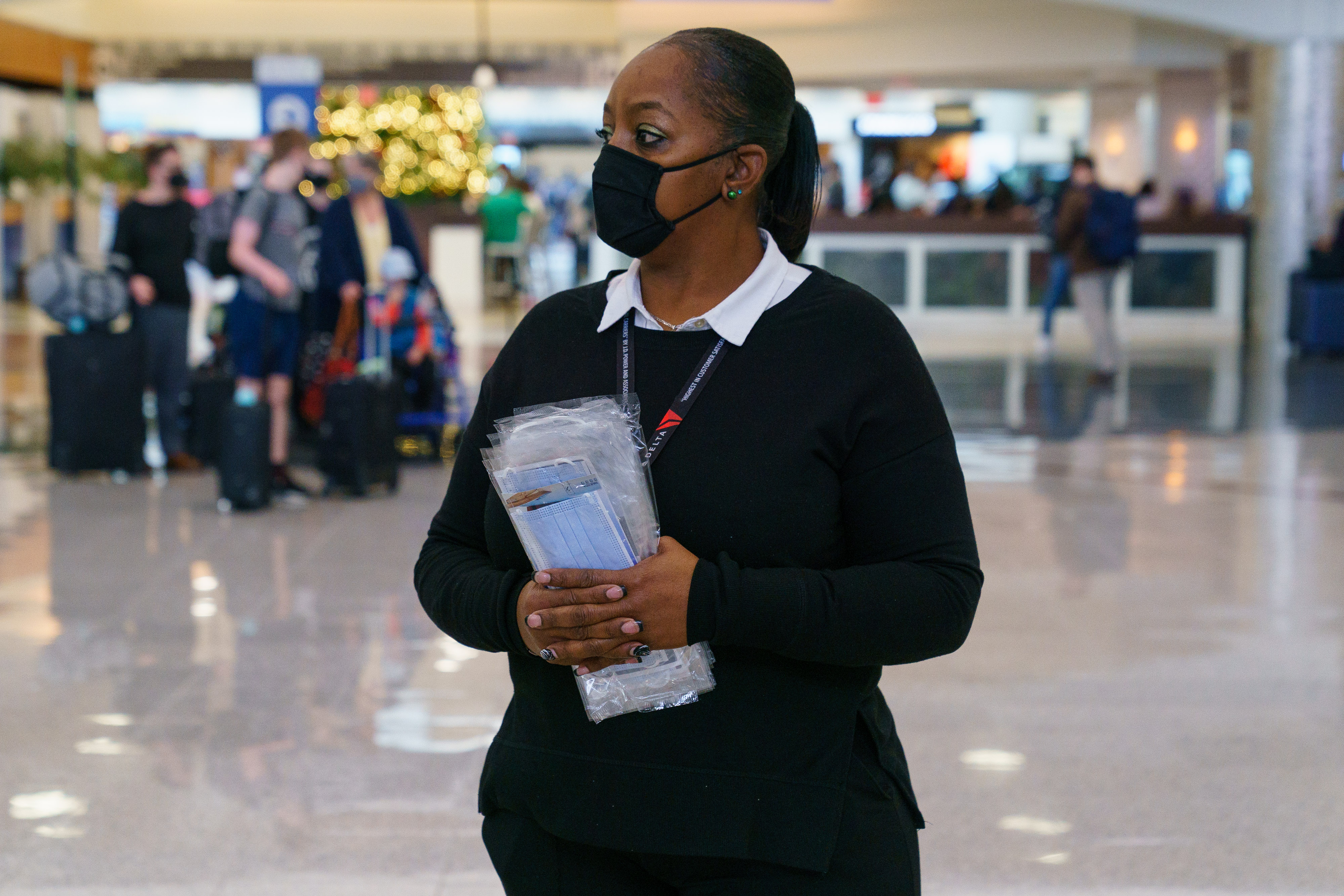 A Delta employee hands out masks to travelers in December 2021