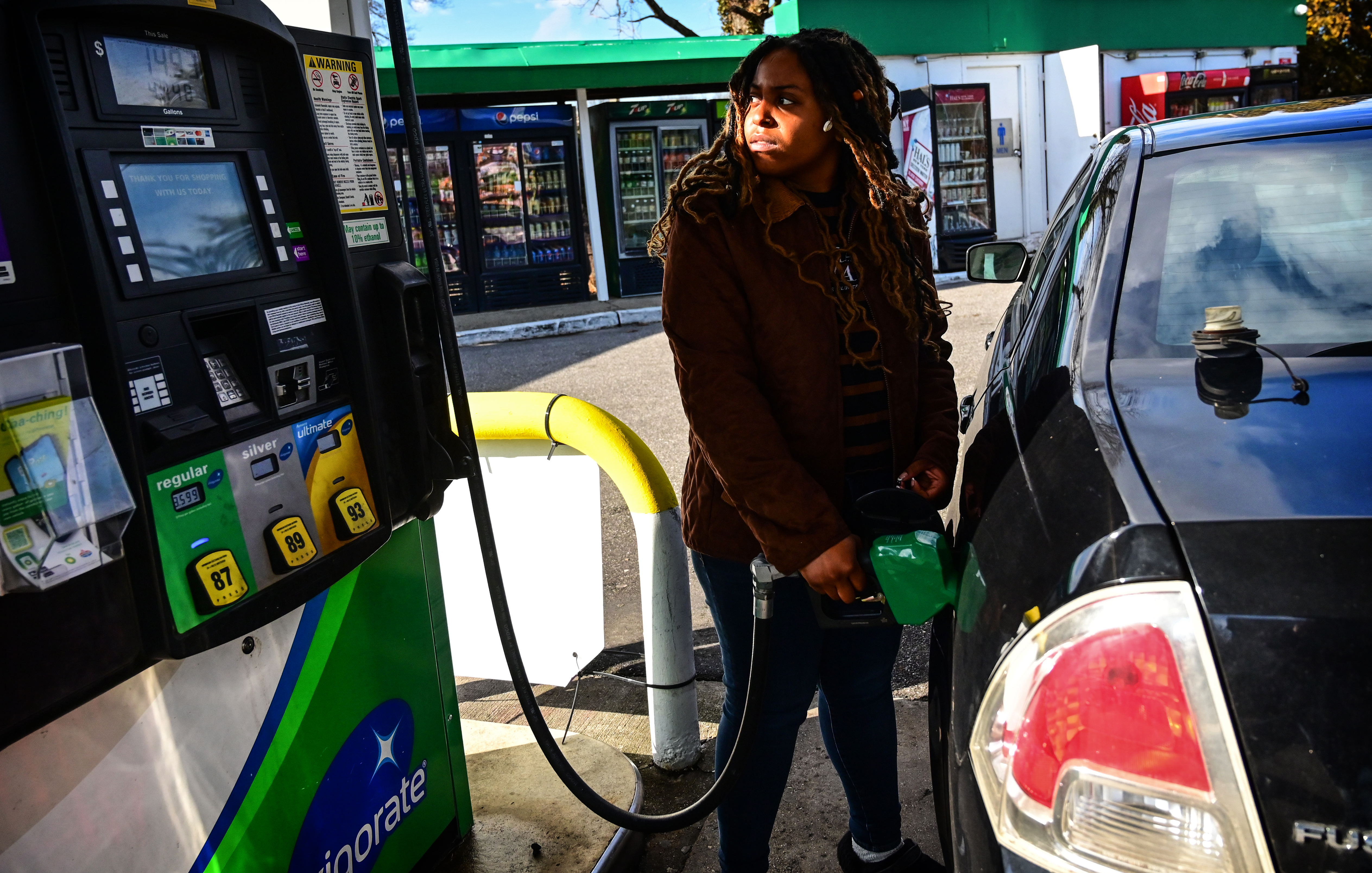A woman pumping gas.