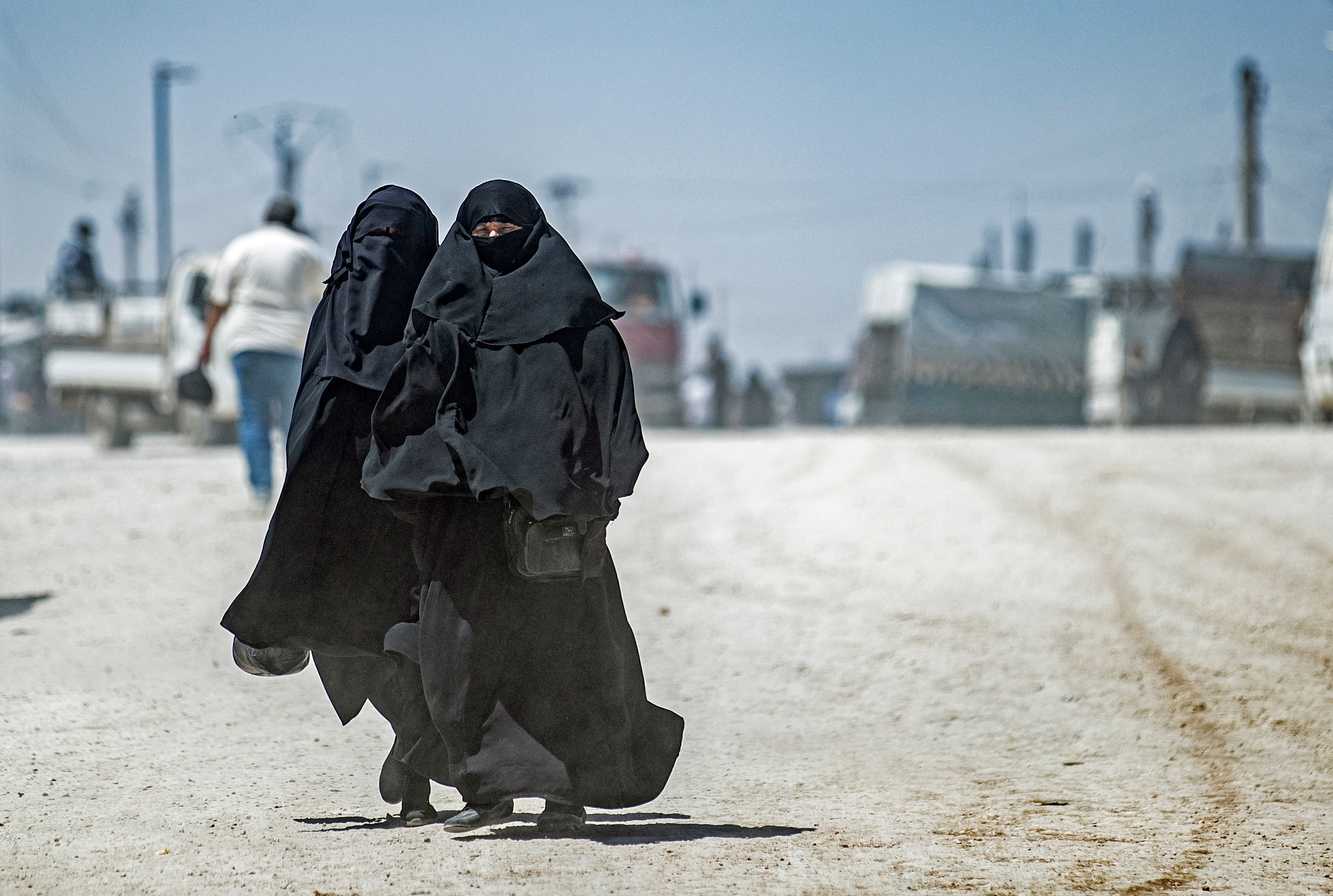 Two women in burqas walk in Syria in 2021