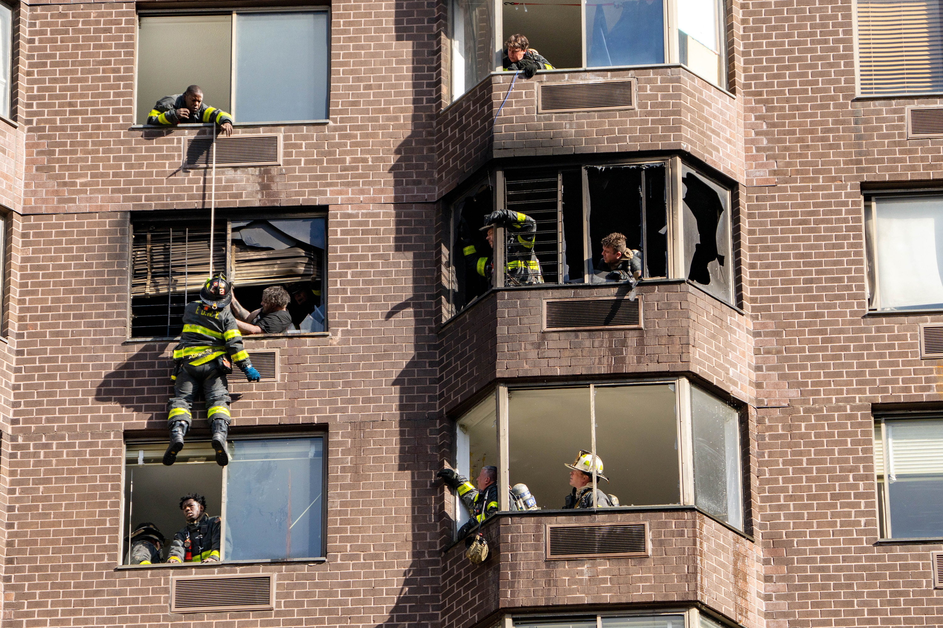Firefighters rescue a woman trapped in a high-rise fire in Manhattan. 