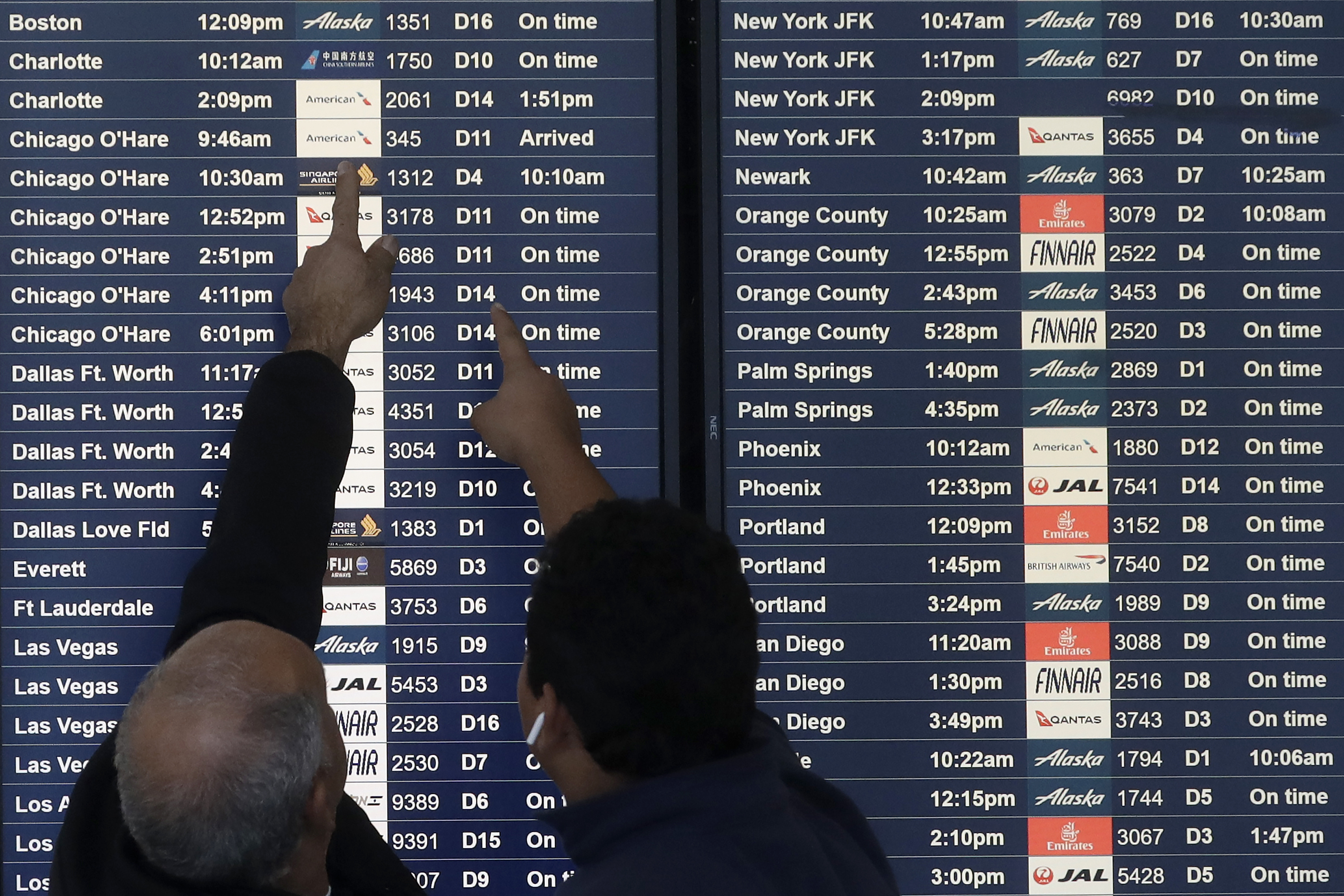 Customers look at travel board in airport.