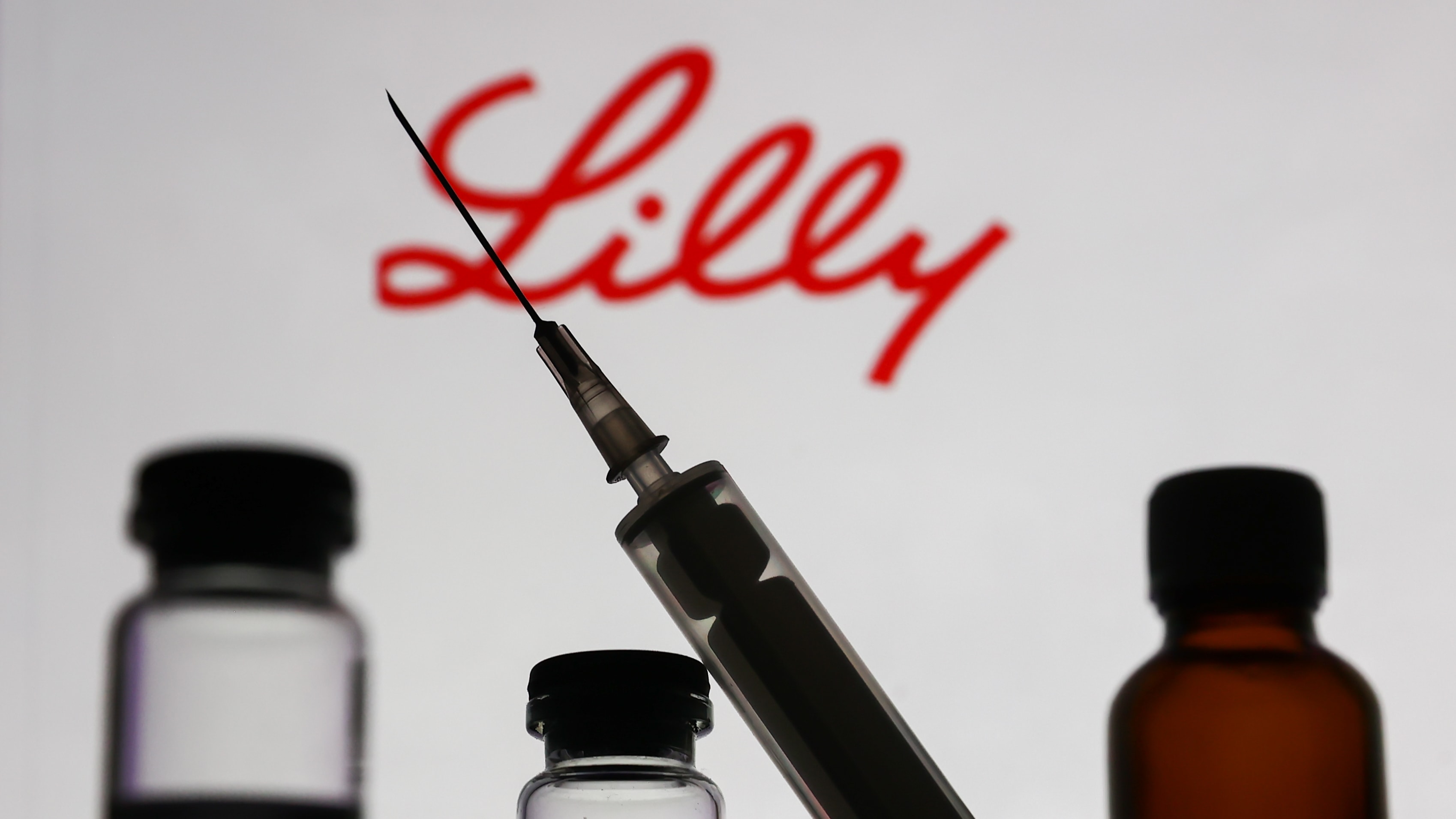Eli Lilly logo with syringe and medicine bottles.
