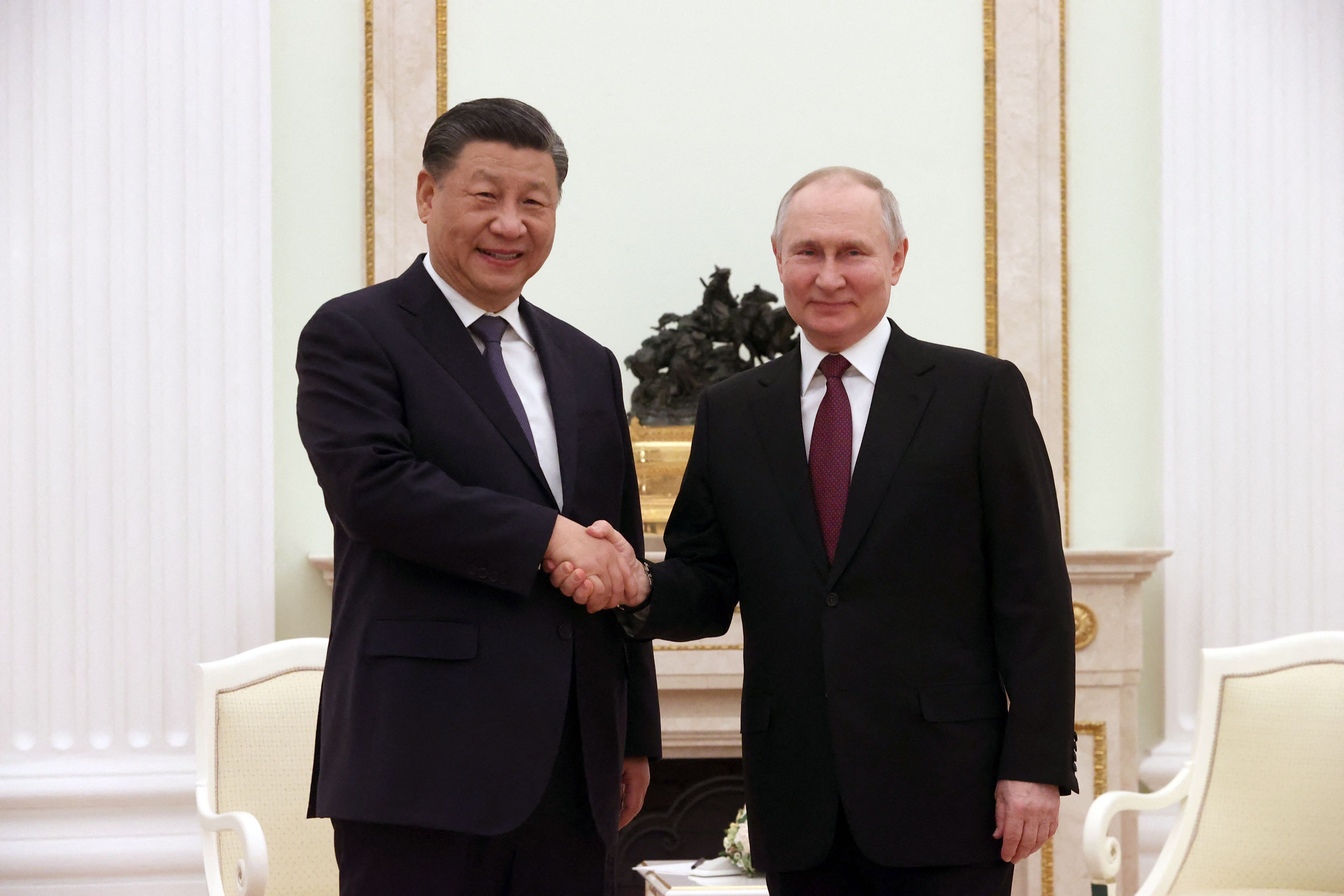 Xi Jinping and Vladimir Putin shake hands
