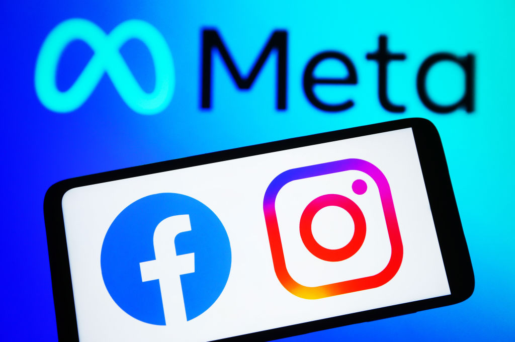 Facebook and Instagram logos on a smartphone and Meta logo on a pc screen